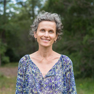 Woman smiling and holding a bottle of supplements.